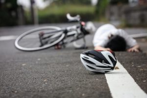 明石市大久保の道路で自転車事故により転倒し、ヘルメットが脱げ、地面に倒れている人